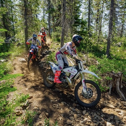 Two ATV riders driving on a sandy trail
